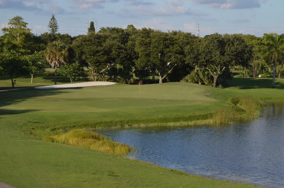 The green, bunker and water at Village Golf Club’s 14th hole.